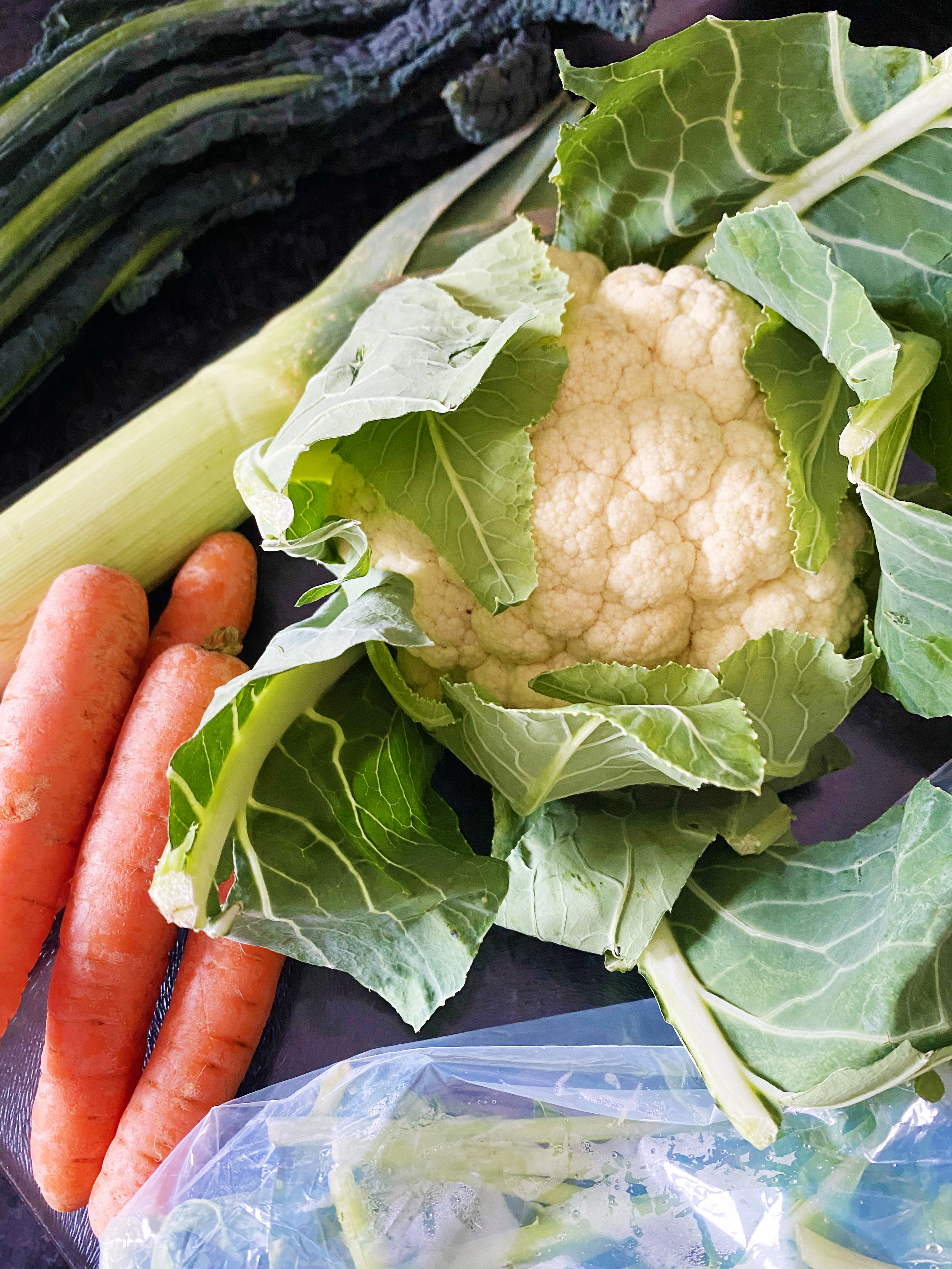 A close up of cauliflower, kale, carrots and leek.