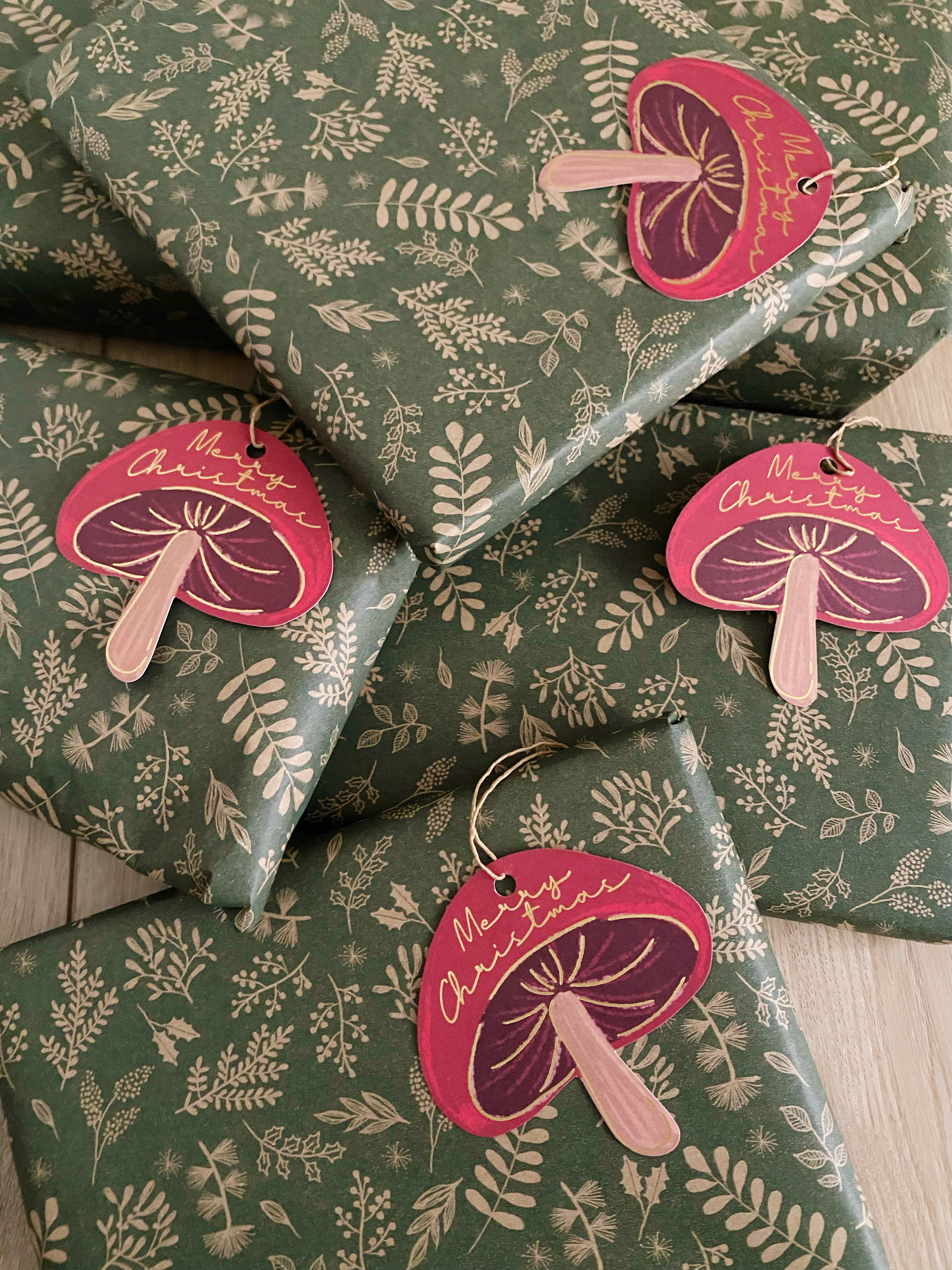 Christmas presents wrapped in green botanical paper with mushroom gift tags.